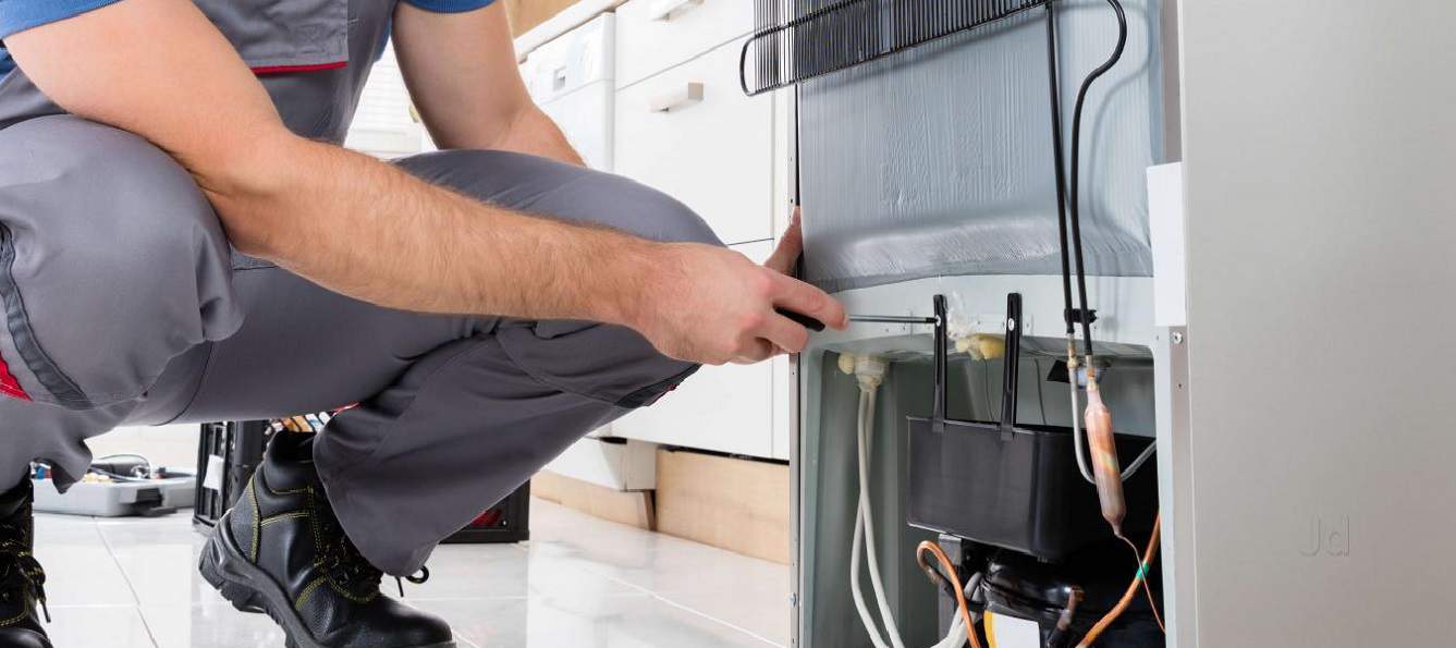 Técnico especializado realizando atendimento domiciliar em geladeira